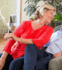 Woman in red shirt smiling, sitting indoors.